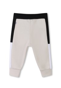 Joggers beige et noirs avec des panneaux latéraux blancs, taille élastique, poignets côtelés et texture lisse. Comprend une étiquette de logo sur la taille.