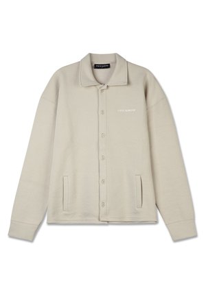 Beige knap-jakke med et tekstureret mønster, stort krave, to forlommer og et subtilt logo på brystet. Blødt stof.