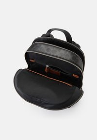 Mochila preta com um exterior de couro texturizado, fechos duplos e um interior espaçoso que inclui um bolso com fecho e um forro de tecido suave.