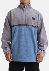 Mikina s polovičným zipsom vyrobená z fleece v modrej a šedej kordovej farbe, s ribbenými manžetami a dekoratívnym pásom so vzorom.