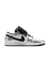 Χαμηλό sneaker με ασημένιες και λευκές επιφάνειες, μαύρο λογότυπο Nike, μαύρα κορδόνια και φλίπ που καλύπτει τη γλώσσα σε λευκό φόντο.