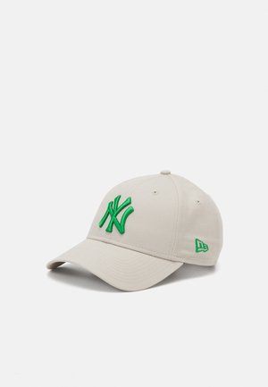 Beige Basecap mit grünem, gesticktem 'NY'-Logo auf der Vorderseite und kleinem grünem Icon an der Seite, aus Baumwollstoff gefertigt.
