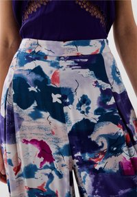 Lichte, multikleurige wijde broek met een mix van abstracte patronen in blauw, roze en paars, met een gladde stof en een aansluitende tailleband.
