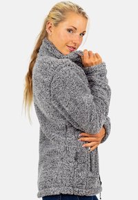 Gray, textured fleece jacket with a high collar, zippered pockets, and a relaxed fit. Features a soft, fluffy exterior for warmth.