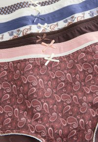 Pile de sous-vêtements en coton pour femmes de différentes couleurs et motifs, chacun avec un petit nœud décoratif au centre de la ceinture.