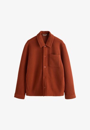 Rust-colored fleece jacket featuring a point collar, front pocket, and snap closure. Soft texture with side pockets, tailored shape.