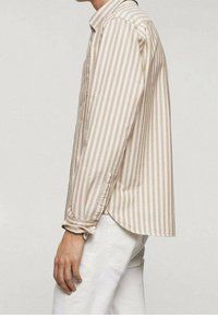 Camisa de manga larga a rayas en beige claro y blanco roto. Cuenta con puños abotonados y un dobladillo ligeramente curvado. Fabricada con una tela suave.