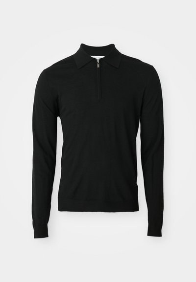 Czarna polo w długim rękawie, wykonana z miękkiego materiału, z kołnierzykiem z pół zamkiem i dopasowanym dołem. Materiał wydaje się gładki i lekko teksturowany.