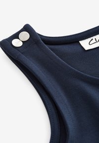Navyblauw mouwloos topje met een gladde textuur, voorzien van twee metalen knopen op de schouder en een label in de halsgenaaid.