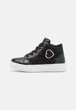Zapatillas altas negras hechas de cuero sintético y tejido texturizado. Presentan ojales dorados y un acento en forma de corazón. Suela de goma blanca.