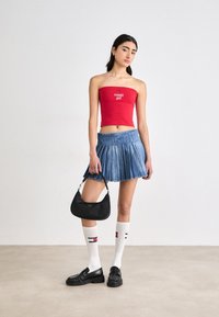 Rdeča brezramna majica z logotipom "tommy girl", modra nabirana jeansa krila, črna torbica, bele nogavice do kolen z rdečimi in modrimi detajli, črne oksfordke.