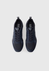 Marine athletic sko med mesh- og syntetisk overdel, rund tå, snøring foran, og logo-detaljer på siden og tungen. Flat såle.