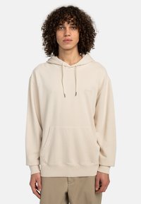 Sudadera de color crema hecha de tela suave, con un bolsillo tipo canguro, cordones y puños y dobladillo de canalé. Marca sutil en el pecho.