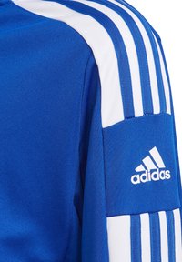 Blue athletic shirt featuring white three-stripe detailing on the shoulder and a white Adidas logo on the sleeve. Textured fabric.