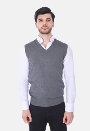 Gilet grigio lavorato a maglia con scollo a V, orlo a costine, indossato sopra una camicia bianca, caratterizzato da una silhouette aderente e una texture liscia.