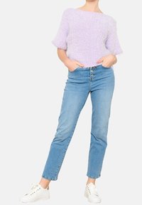 Vaalean lilafa knitted-paita, jossa on lyhyet hihat, yhdistettynä vaaleansinisiin farkkuihin, joissa on nappikiinnitys. Valkoiset lenkkarit täydentävät asua.