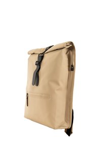 Beige vanntett ryggsekk med rull-opp åpning, svart festemateriell, frontlomme med glidelås og justerbar stropp, med glatt tekstur og minimalistisk design.