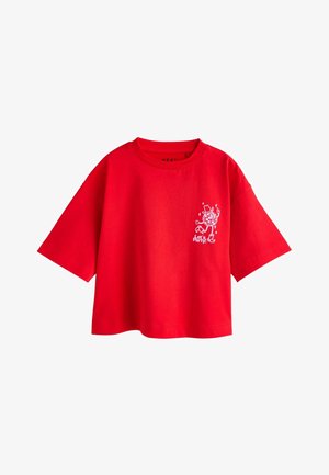 Tricou din bumbac roșu cu mâneci scurte, croială lejeră și un grafic imprimat alb pe partea stângă care prezintă un personaj și stele.