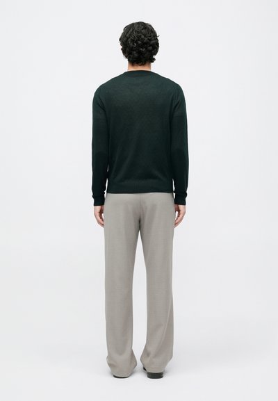 Dark green knit sweater with ribbed cuffs and hem, paired with light gray tailored trousers, viewed from the back. Smooth texture.