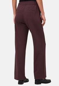 Bordeauxkleurige, wijde broek met een gladde textuur. Kenmerkt zich door een elastische tailleband, twee achterzakken en een rechte snit tot aan de zoom.