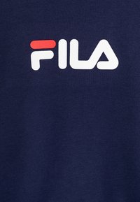 Mörkblå t-shirt med en vit och röd FILA-logotyp. Tyget är mjukt med en subtil textur och har en klassisk rund hals design.