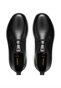 Scarpe nere in pelle con finitura liscia, punta arrotondata, lacci minimi e marchio discreto all'interno della scarpa. Fodera interna morbida.