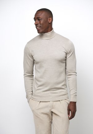 Beige Rollkragenpullover, taillierte Passform, gerippte Bündchen und Saum, glatte Textur. Kombiniert mit hellbeigen Cordhosen.