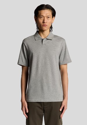 Polo shirt gris en mélange de coton, avec des manches courtes, un col classique et une patte de boutonnage à deux boutons. Le modèle porte un pantalon cargo olive.