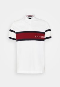 Valkoinen polo-paita, jossa on punainen ja tummansininen vaakaraita, jossa on "HILFIGER"-logo. Lyhyet hihat, joissa on tummansiniset yksityiskohdat. Puuvillamateriaali.