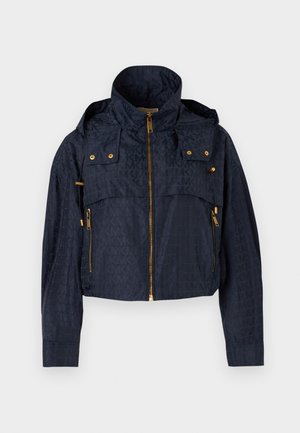 Jachetă scurtă bleumarin cu glugă, fermoar auriu și detalii cu nasturi, cu un model subtil repetitiv al logo-ului „MK”.