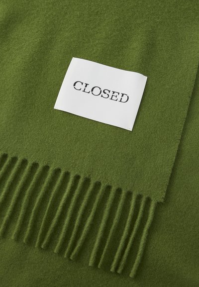 Green wool scarf with fringed edges, featuring a white label with the word "CLOSED" in black text. Smooth texture, rectangular shape.