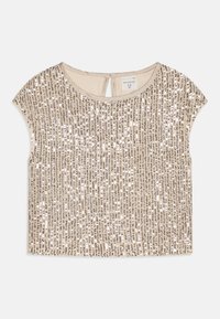 Haut beige à manches courtes orné de rangées verticales de paillettes argentées et dorées. Il présente un col rond et une petite ouverture à l'arrière.