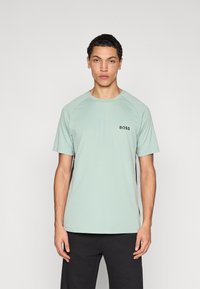 Lichtgroen T-shirt met ronde hals en raglanmouwen. Voorzien van een klein zwart "BOSS"-logo op de borst. Gladde textuur, gemaakt van zachte stof.