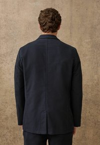 Marineblazer mit strukturiertem Design, featuring einen Reverskragen, geradem Schnitt und sichtbaren Nahtdetails. Aus einem glatten Material gefertigt.