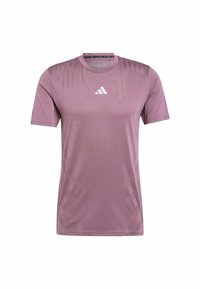 Jasnoliliowa sportowa koszulka z krótkim rękawem i okrągłym dekoltem. Posiada subtelne wzory w paski oraz białe logo Adidas na piersi. Gładki materiał.