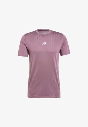 Jasnoliliowa sportowa koszulka z krótkim rękawem i okrągłym dekoltem. Posiada subtelne wzory w paski oraz białe logo Adidas na piersi. Gładki materiał.