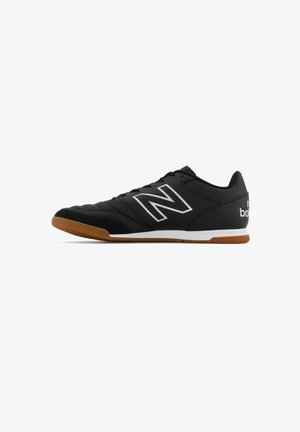 Black athletic shoes with a textured leather upper, white and silver logo accents, and a gum rubber sole. Features a lace-up front and padded collar.