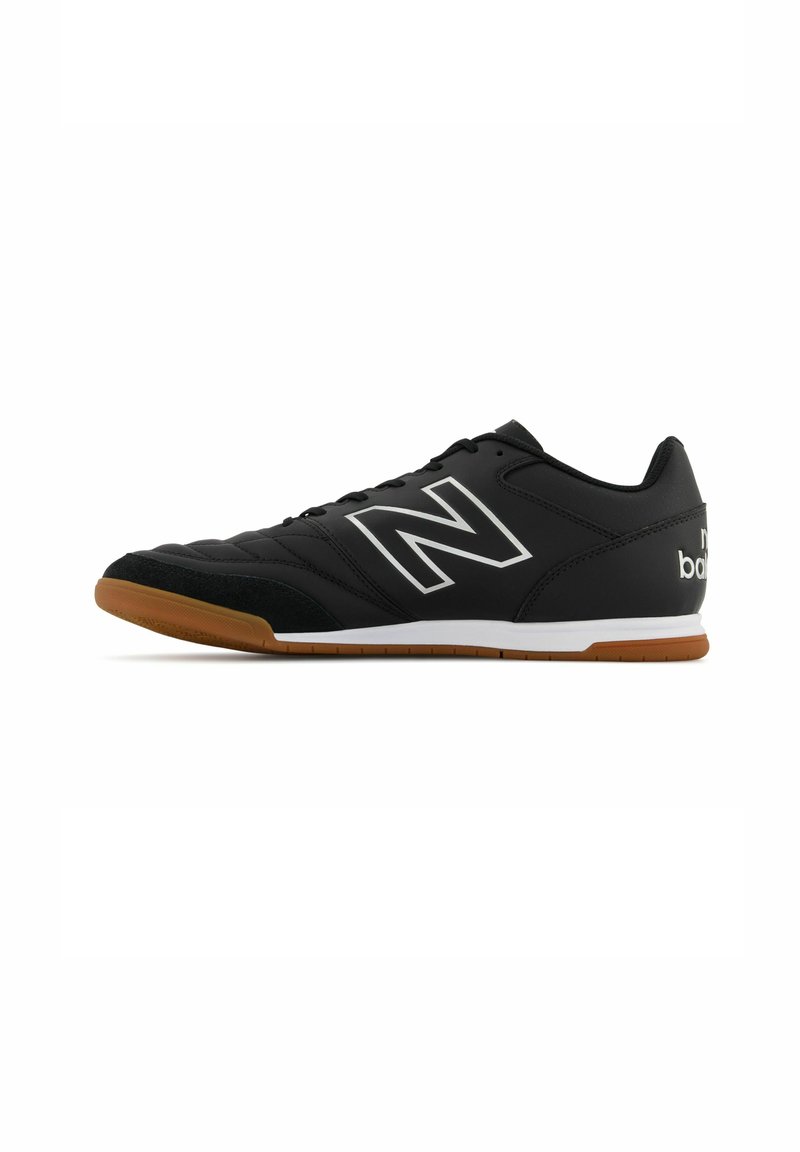 Baskets de sport noires avec une tige en cuir texturé, des accents de logo blancs et argentés, et une semelle en caoutchouc gomme. Présentent un système de laçage à l'avant et un collier rembourré.