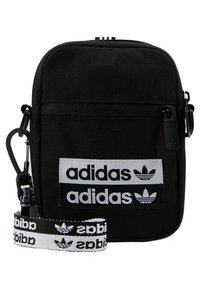 Černá plátěná crossbody taška se dvěma bílými logo nášivkami, nastavitelným popruhem a zipovým uzávěrem. Vyznačuje se minimalistickým designem a obdélníkovým tvarem.