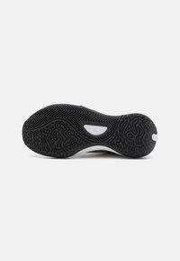 Shoe sole with a black rubber material featuring textured patterns and herringbone design, contrasting white midsole with logo detail.