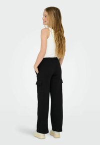 Mustat cargo-housut, joissa on elastinen vyötärö ja sivutaskut, yhdistettynä valkoiseen toppiin. Kangas näyttää kevyeltä ja hengittävältä.