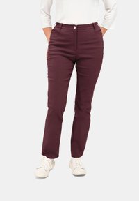 Bordeaux slim-fit broek met een gladde textuur, voorzien van een voorknopsluiting en zijzakken, gecombineerd met witte sneakers.