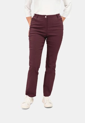 Burgunderfarbene Slim-Fit-Hosen mit glatter Textur, ausgestattet mit einem frontalen Knopfverschluss und Seitentaschen, kombiniert mit weißen Sneakern.