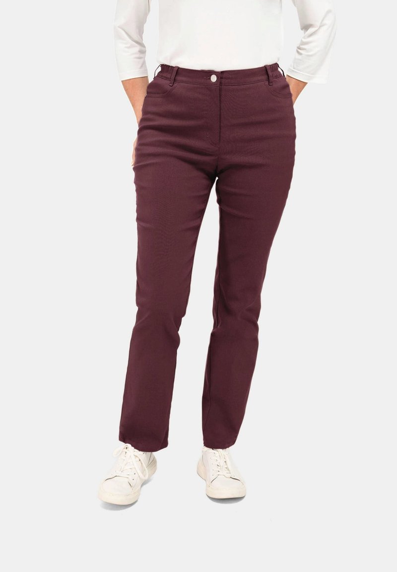 Bordeaux slim-fit broek met een gladde textuur, voorzien van een voorknopsluiting en zijzakken, gecombineerd met witte sneakers.