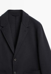 Navy wool blend blazer with a notched collar, single chest pocket, and two button closures, featuring a soft, textured surface.