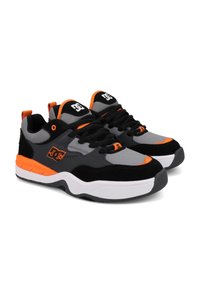 Sneakers DC w szarym cholewce z czarnymi i pomarańczowymi akcentami, wykonane z siateczki i zamszu, z gumową podeszwą, okrągłym noskiem i czarnymi sznurowadłami.