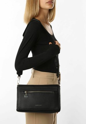 Sac bandoulière en cuir noir avec une poche zippée à l'avant et un accent métallique. Doté d'une sangle détachable et d'une surface texturée. Forme rectangulaire compacte.