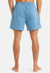 Light blue swim shorts made of smooth fabric, featuring an elastic waistband, single back pocket, and a solid plain design.