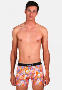 Boxers colorés avec des motifs floraux en orange, rose et bleu, dotés d'une ceinture élastique noire avec le logo "WAXX".