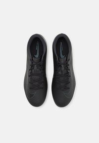 Scarpe da atletica nere con una tomaia testurizzata, caratterizzata da un motivo a spina di pesce. Include lacci neri e un sottile accento blu sul logo Nike.